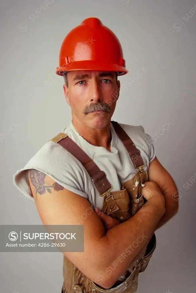 Studio shot of a construction worker wearing a red hard hat. 