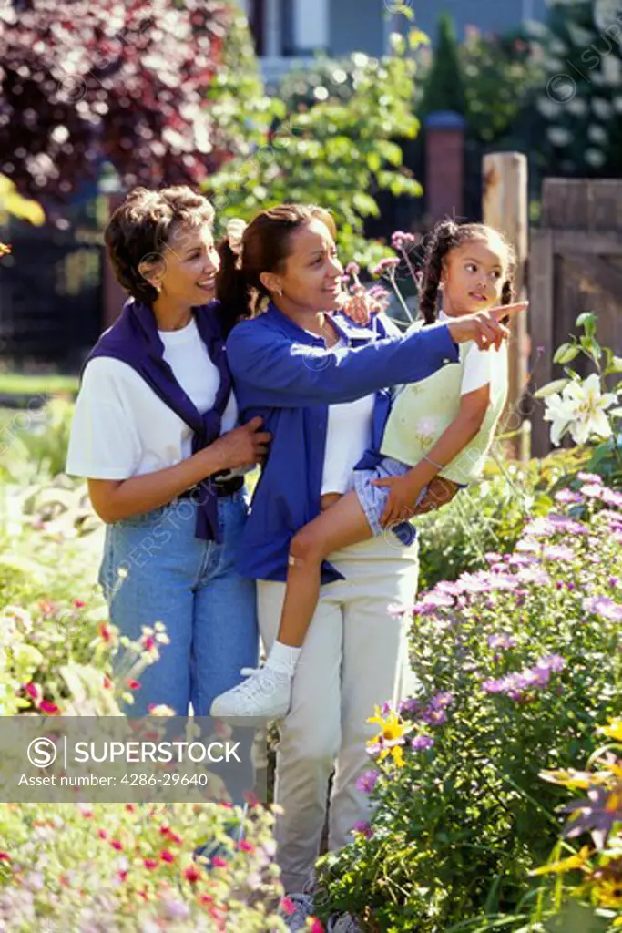 Three generations of African-American women walking outside admiring the colorful flowers.  