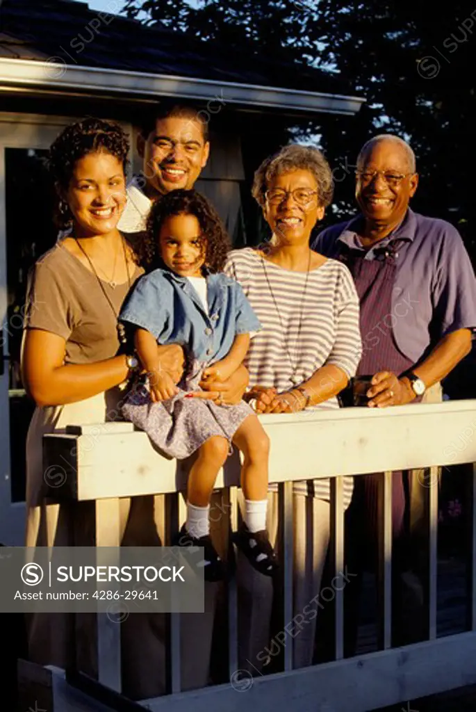 Portrait shot of three generations of an African-American family standing outside on the patio deck. 