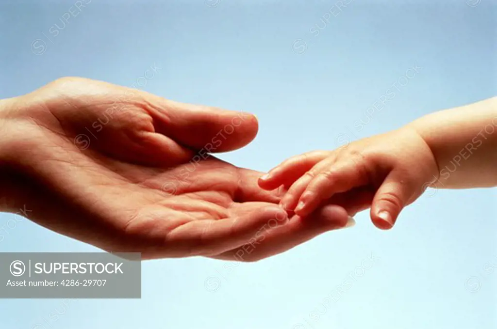Adult hand reaching for babys hand