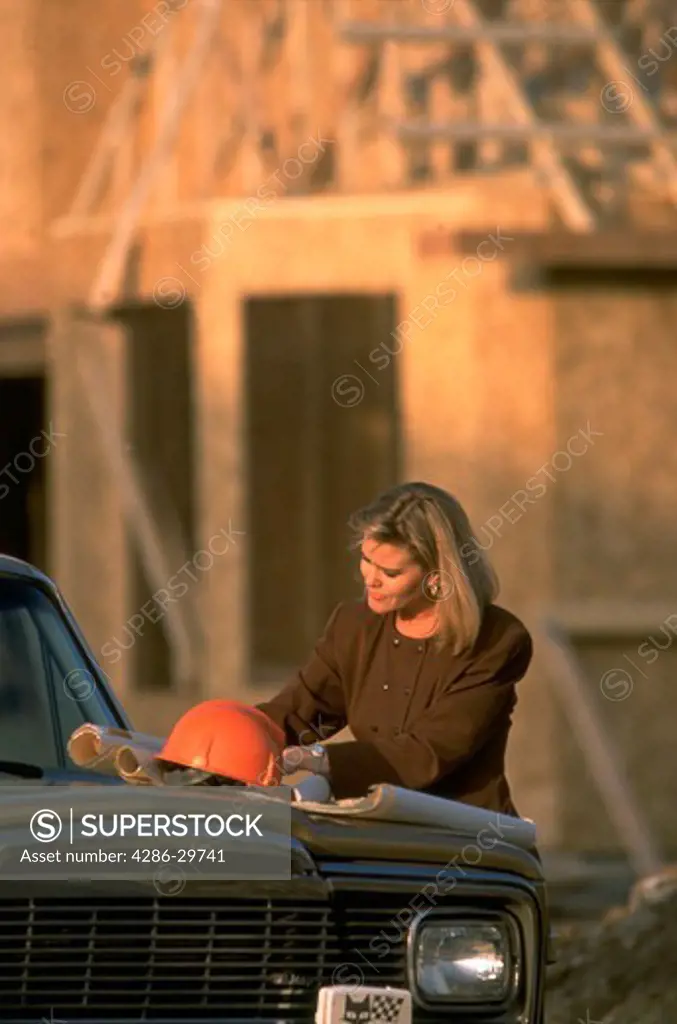Businesswoman at construction job site going over plans.  V/H other variations.