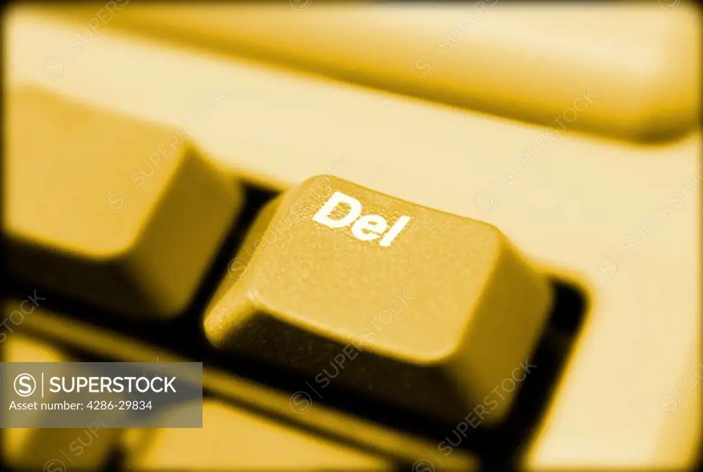 Close-up of 'Delete' key on computer keyboard with yellow light.