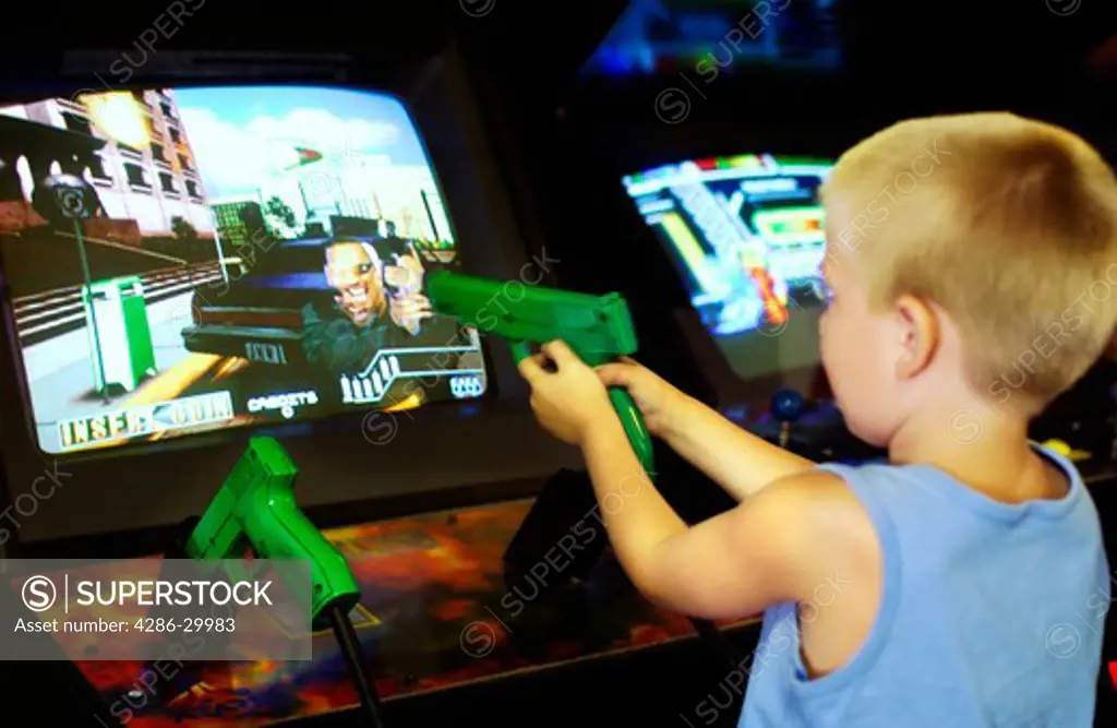 Young boy aiming toy gun at arcade game screen