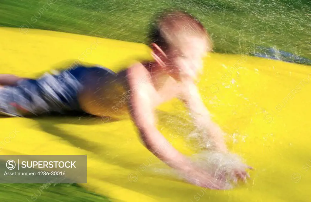 Young boy sliding on a water slide