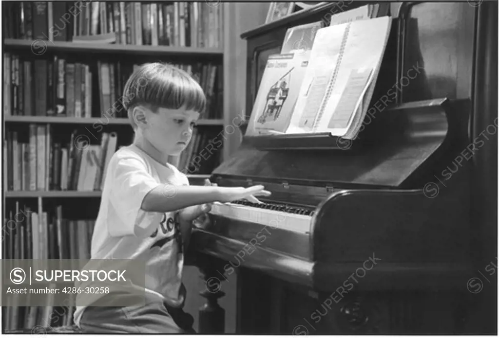 Young boy practicing playing the piano.