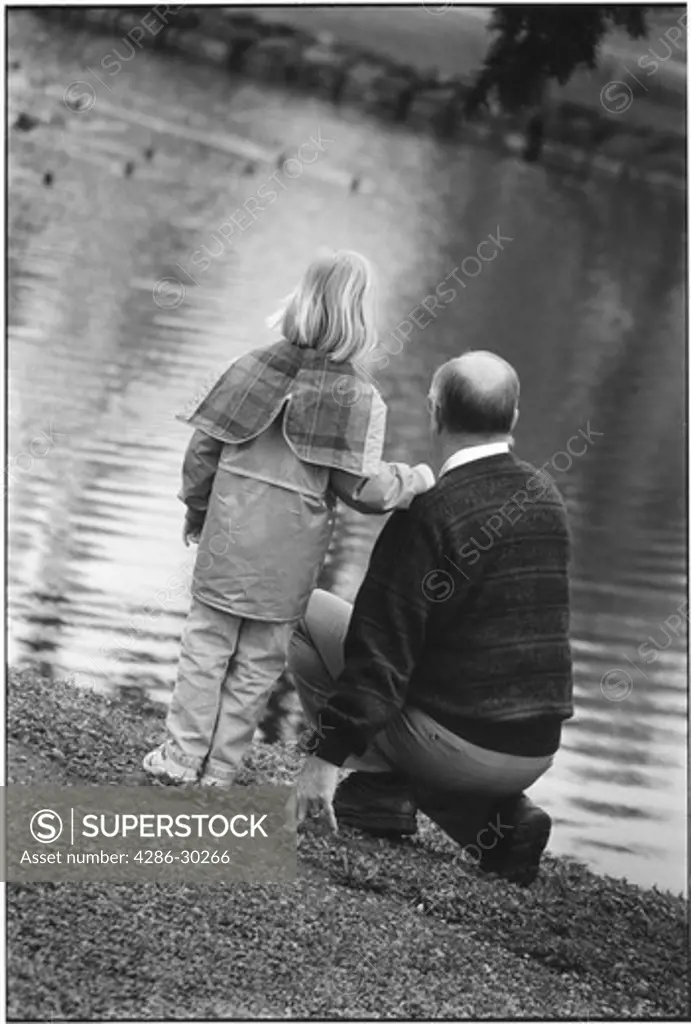 Grandfather and granddaughter at lake.