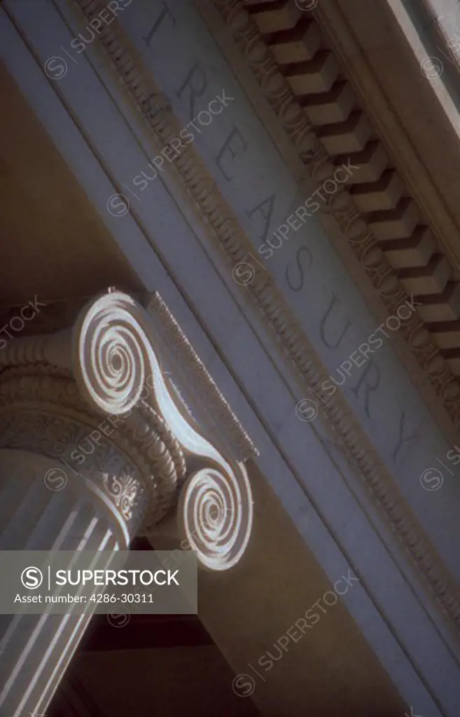 Close-up of the top of a column and the word Treasury on the front of the Treasury Building in Washington, District of Columbia.