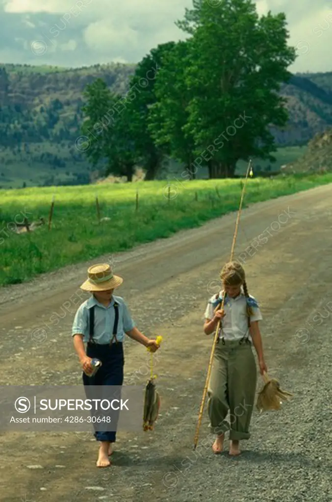 Gone fishing. Children walk a Montana country road.