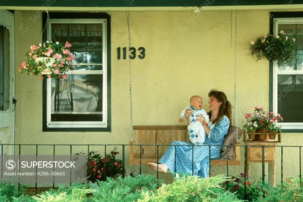 Mother and baby relax on front porch swing.