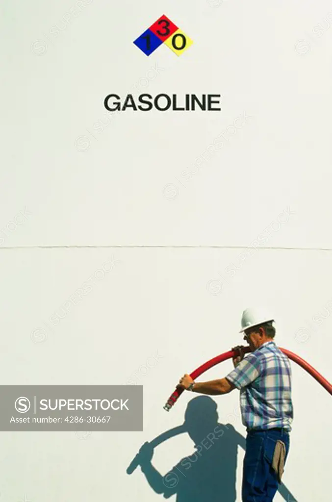 Refinery employee by gasoline storage tank.