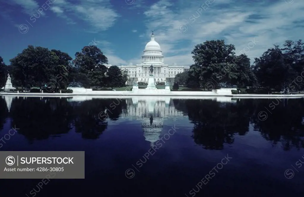 West front of the U.S. Capitol as seen from across the Capitol Reflecting Pool on a summer day.