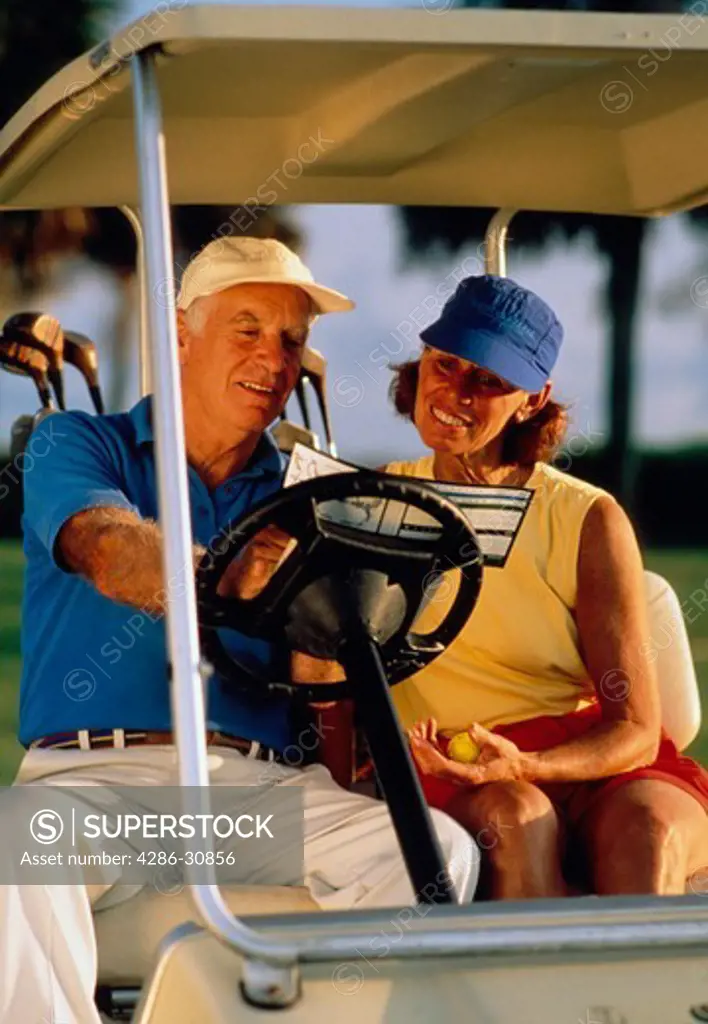 Senior couple sitting in golf cart and looking at score card while playing golf together, Hilton Head Island, South Carolina.