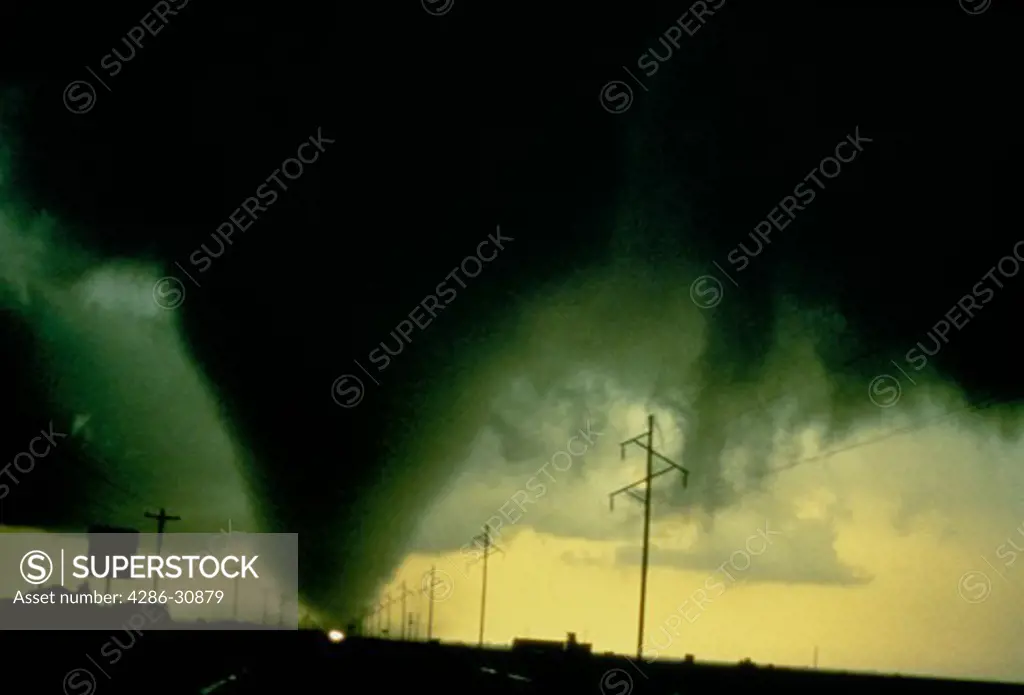 NOAA photo of a fat, conical, tornado touching ground between power lines, Dimmitt, Texas, June 12, 1995.