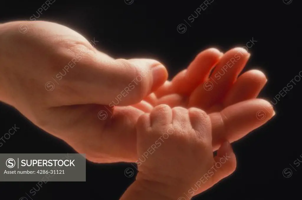 Mother is holding out her hand as her newborn grasps her finger. 