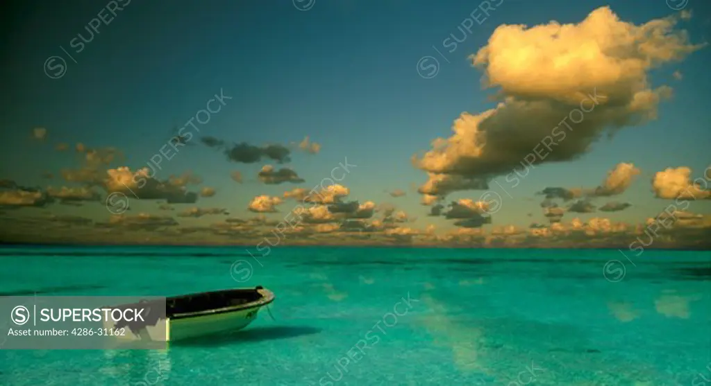 A lone rowboat moored in calm blue water with dark clouds against an erie sky, Isla Mujeres, Mexico.