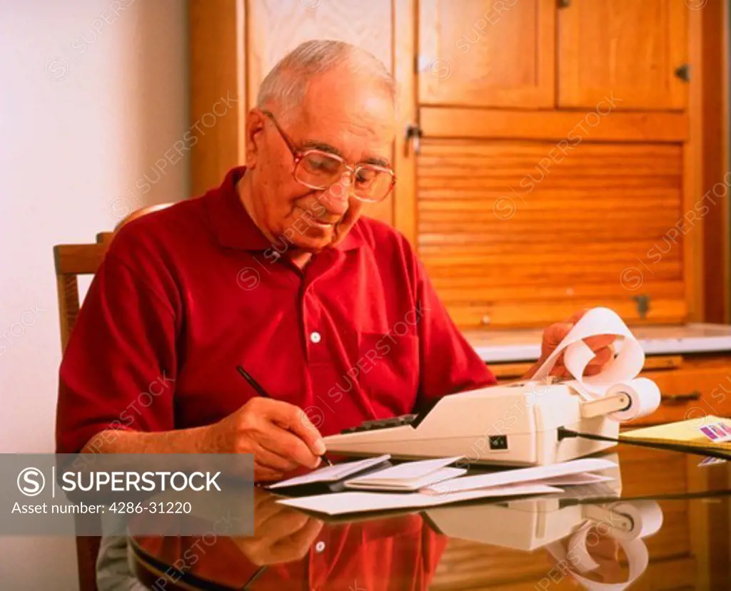 Senior man paying bills at kitchen table