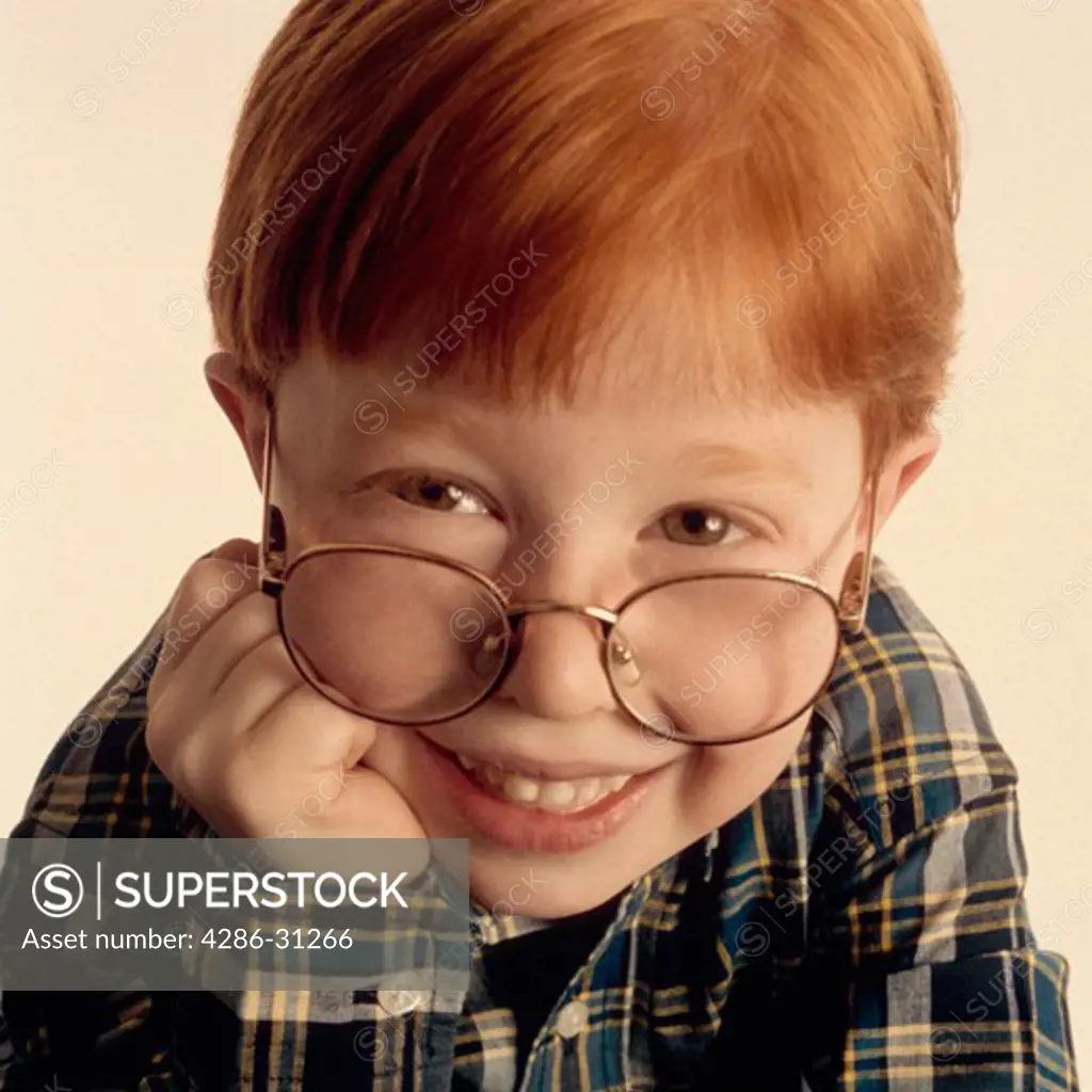 Portrait of young boy with red hair and glasses.