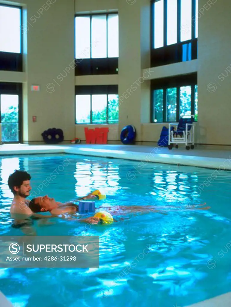 Male rehabilitation specialist doing therapy with a patient in a swimming pool.
