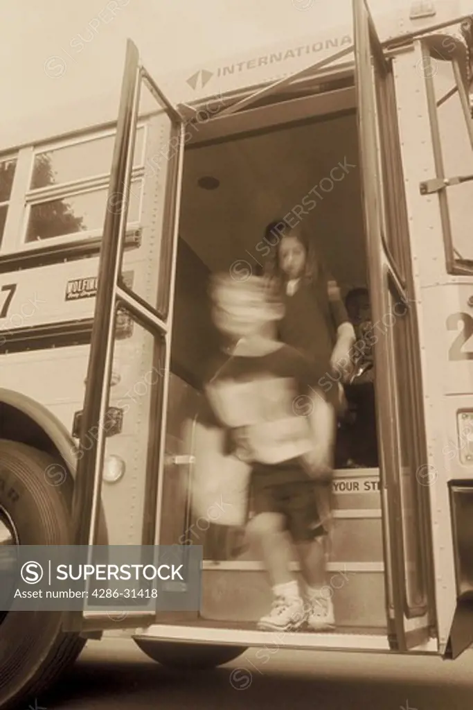 Black and white blurred image of children departing from a school bus on their way home. 