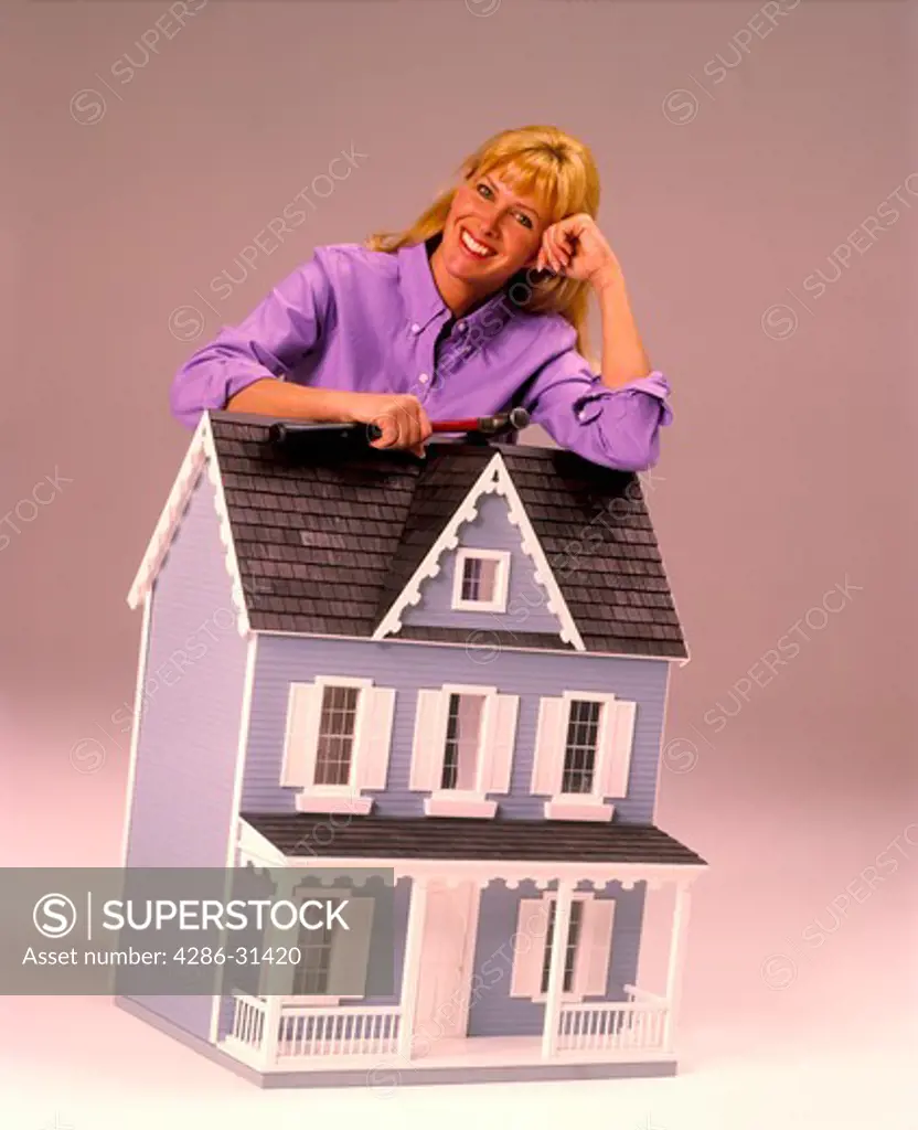 Portrait of an Anglo woman  leaning against a model home symbolizing banking and home mortgages.