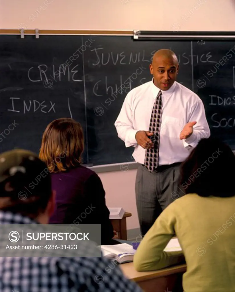 African-American professor standing in front of his class teaching either sociology or criminology. 