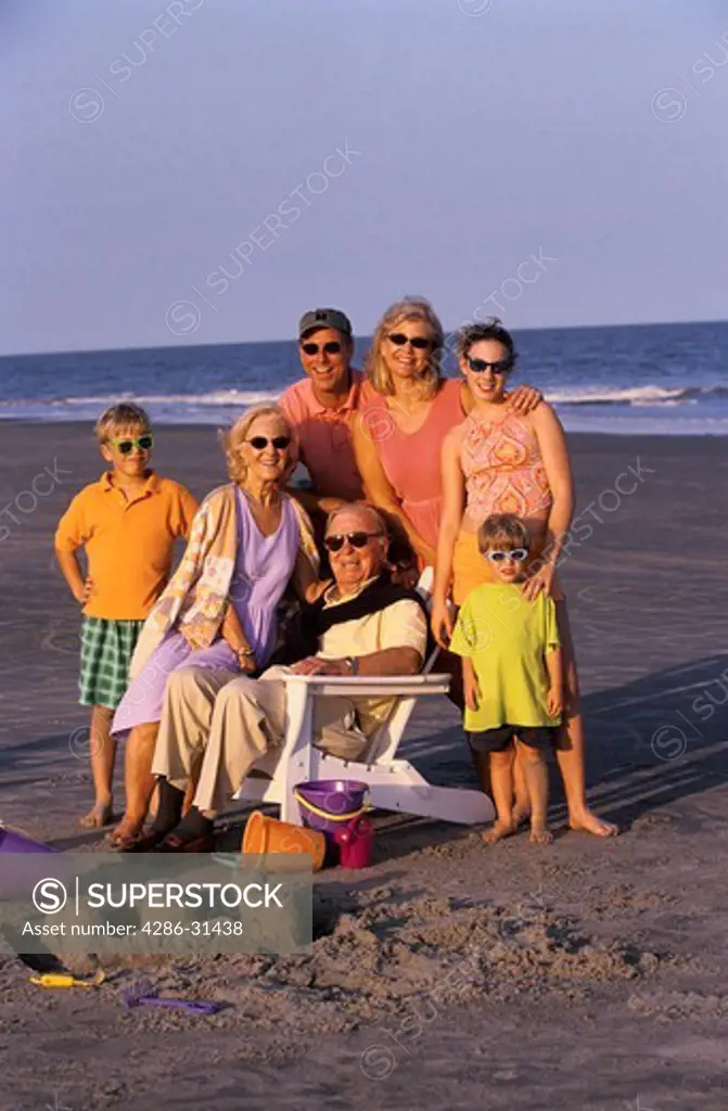 Portrait of an extended family joined together at the beach including parents, grandparents and children.