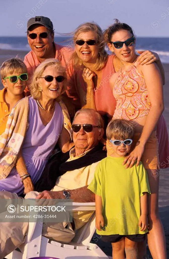 Portrait of an extended family joined together at the beach including parents, grandparents and children.