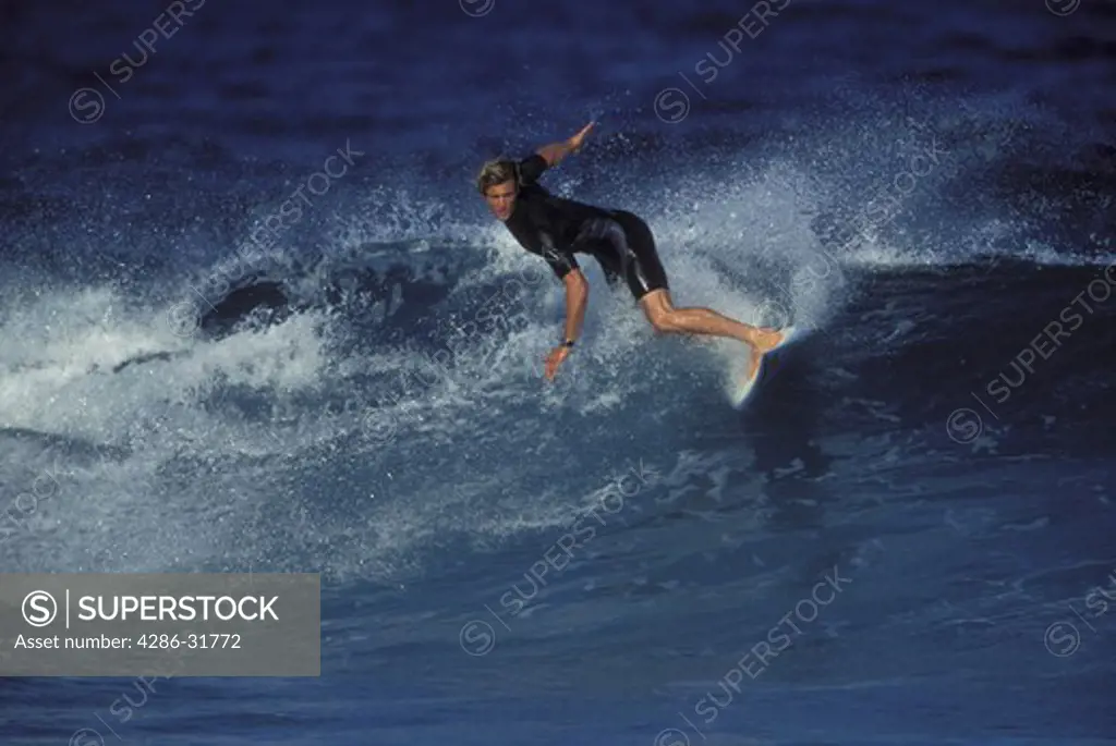 Man surfing along the top edge of a curling wave.