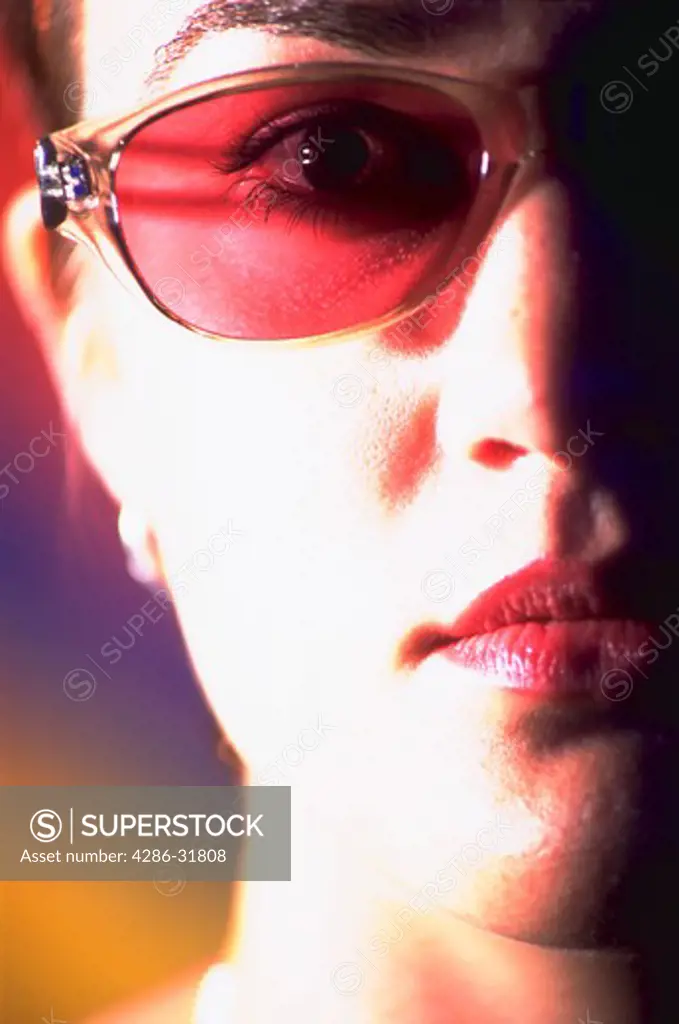 Close-up image of half of a womans face. The woman is wearing tinted glasses.