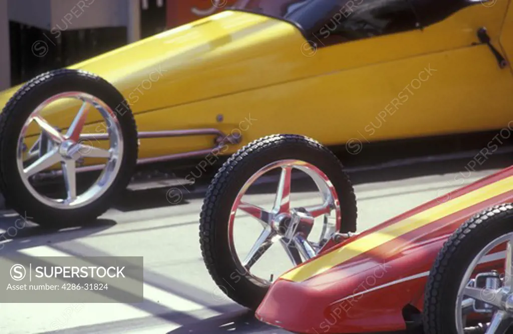Close-up of the front wheels of two amusement park dragsters as they wait on the starting line.