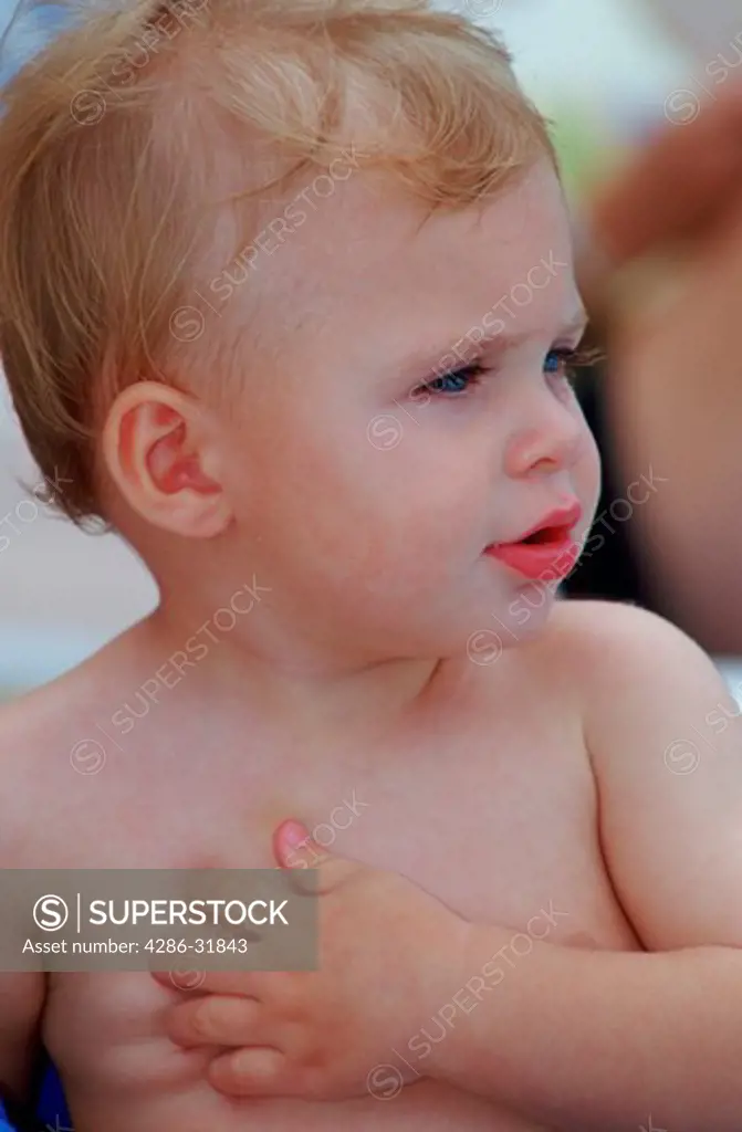 Close-up of a blonde-haired, blue-eyed toddler boy. 