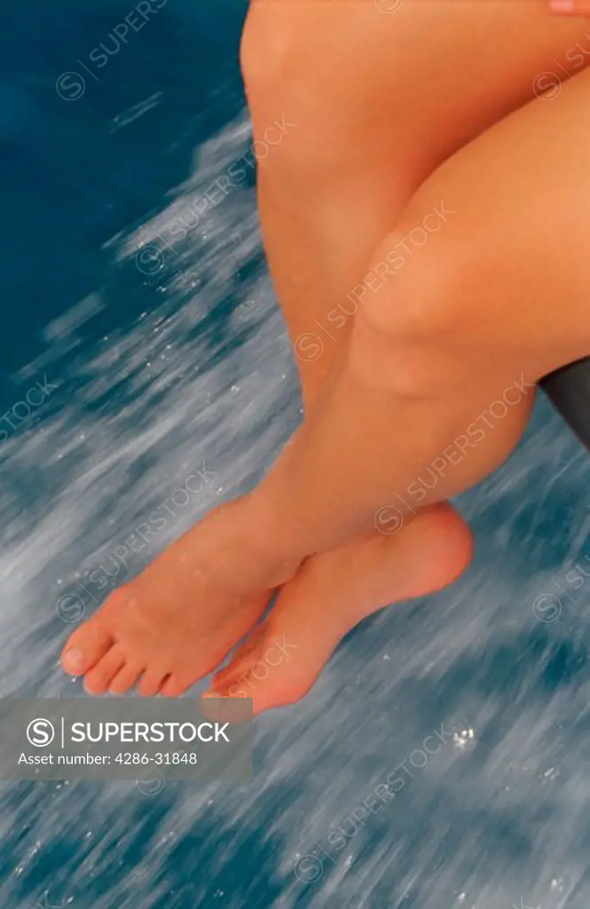 Close-up of a pair of legs hanging from the edge of a boat. 