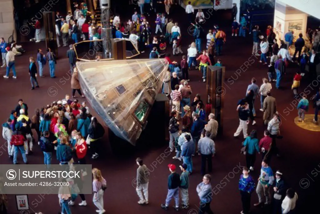 Tourists in the main lobby of the National Air & Space Museum gather around the Apollo 11 capsule Columbia.