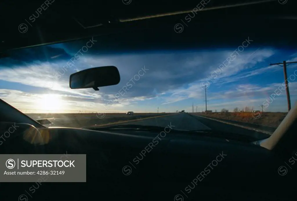 View of the sunset as seen through the front window of a car while driving on US Highway 84 in Lubbock, TX.