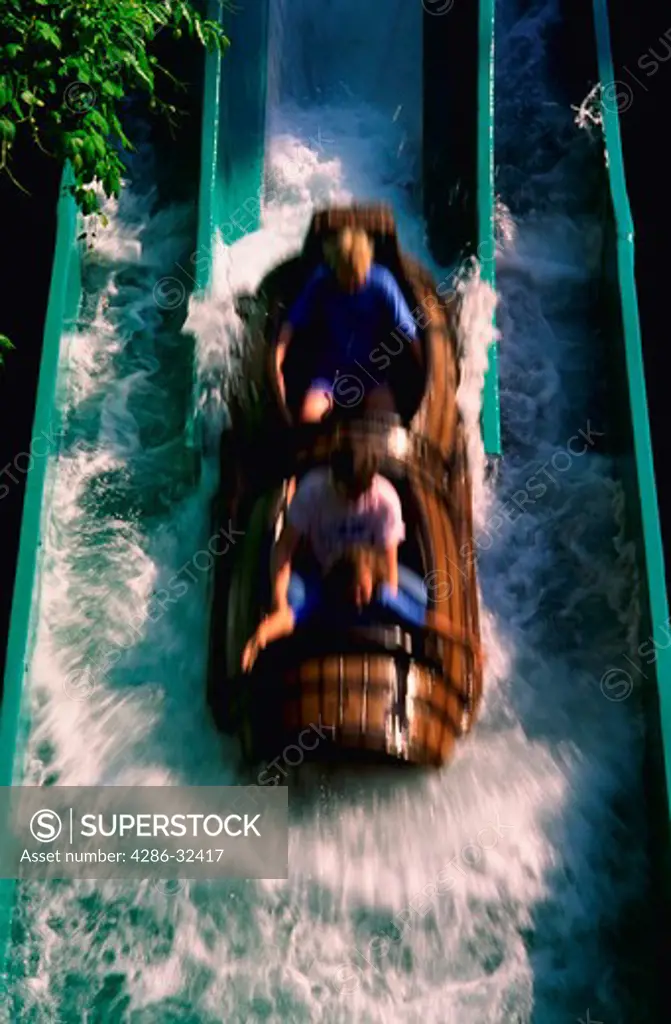Blurred view of three people riding the log flume amusement park ride at Busch Gardens Theme Park in Virginia.