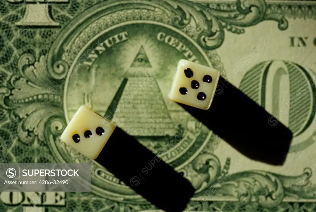 A pair of dice lie on the backside of a one dollar bill. 