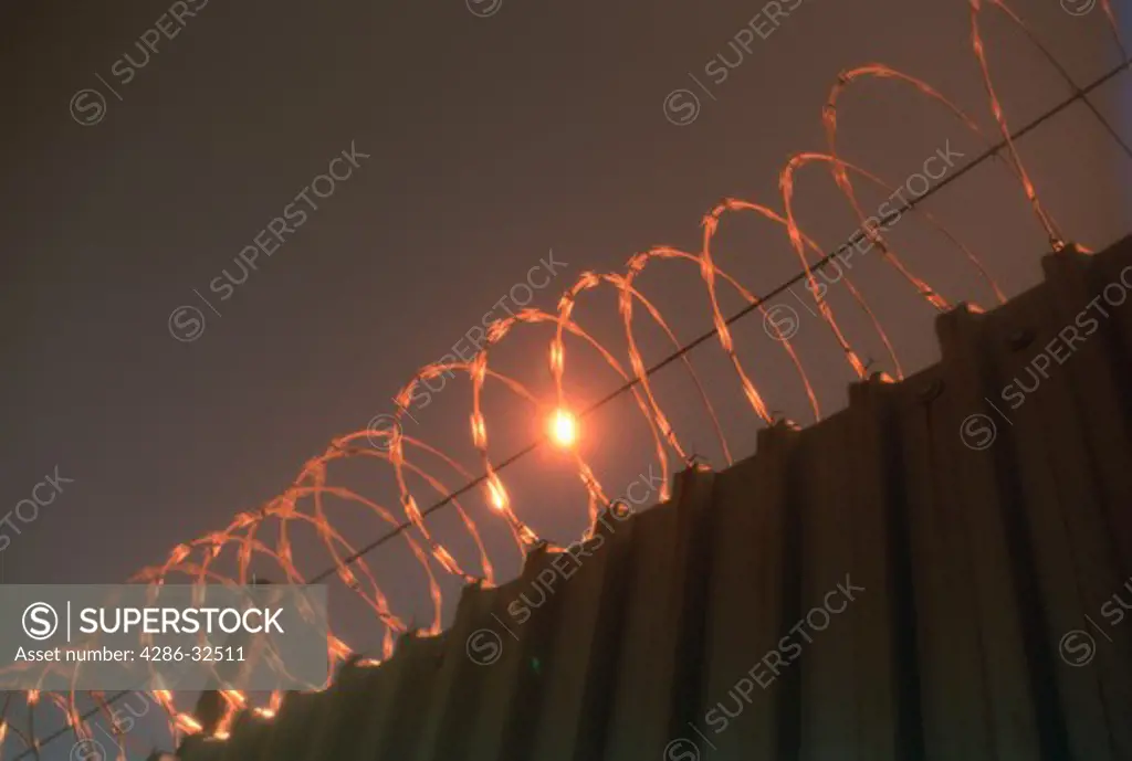 Razor wire on prison security fence with morning sun reflected,