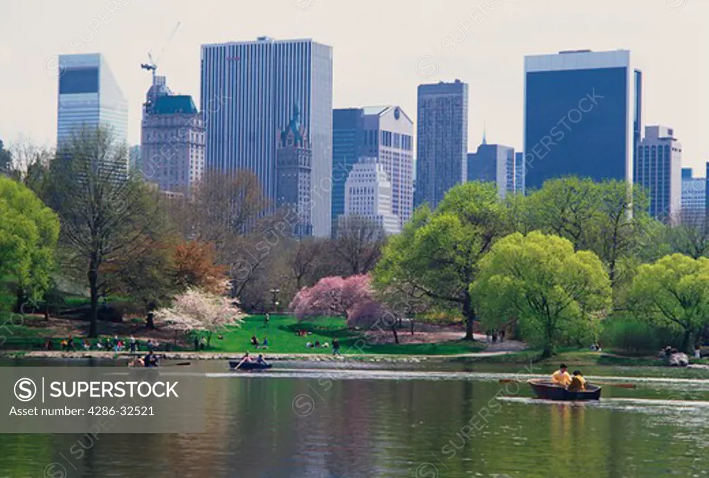 Springtime at the lake in Central Park with rowboats, Midtown skyline, New York City, NY.
