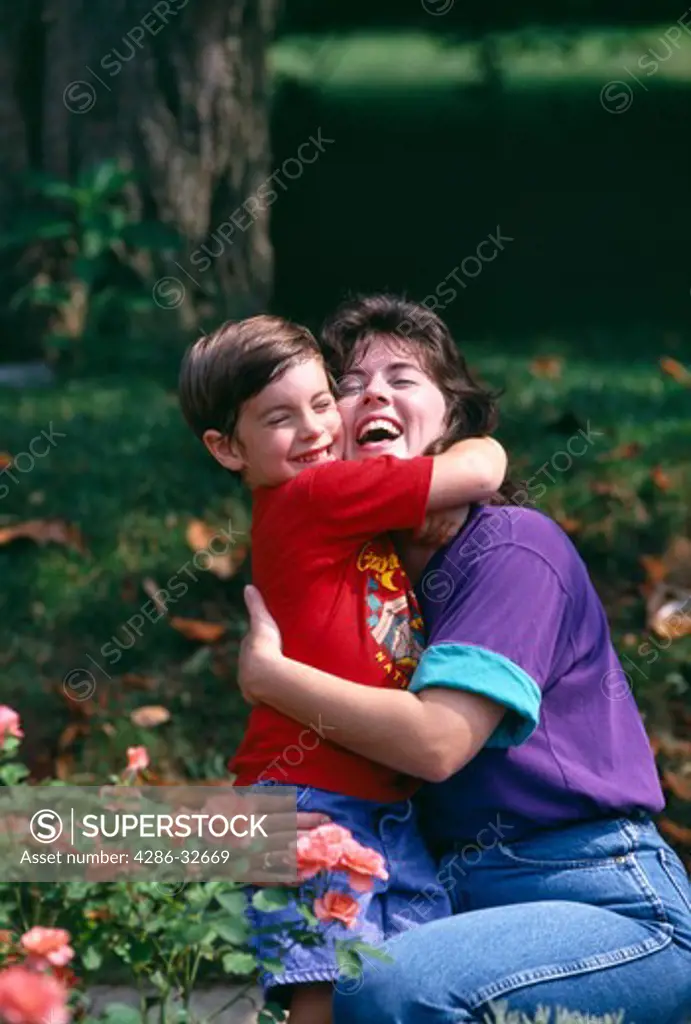 Joyous Hug, mom and son embrace in summer sun while enjoying garden.