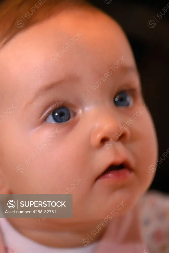 Portrait of young wide-eyed baby looking up.