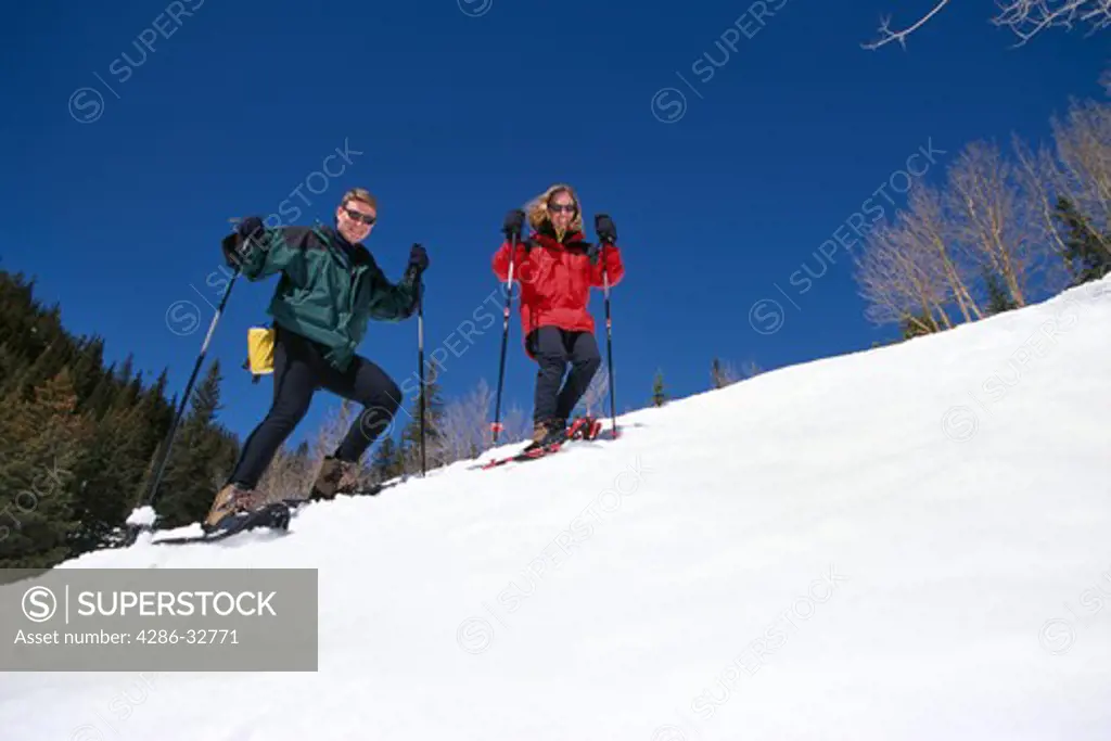 Couple snowshoeing together on a steep slope in the Rocky Mountains.
