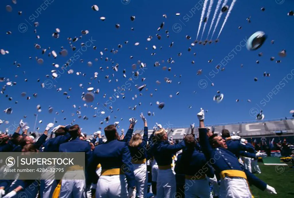 The United States Air Force (USAF) Thunderbirds fly over as USAF Academy Cadets toss their caps in the air at the completion of graduation ceremonies.