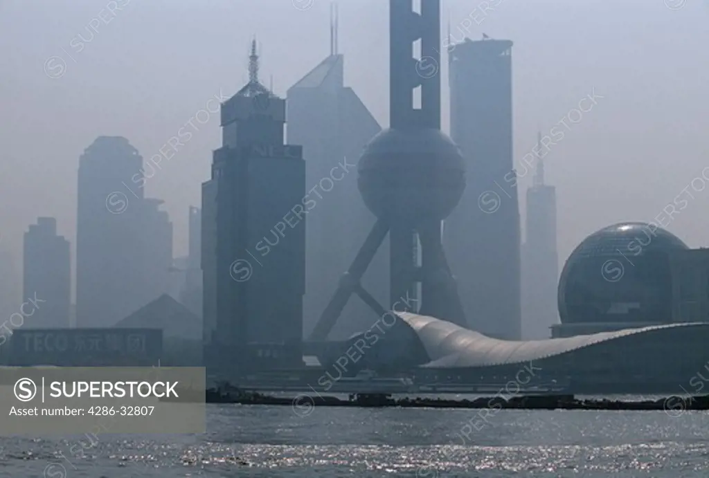 Barges on the Huangpu River crossing in front of the Pudong New Area on a hazy morning in Shanghai China