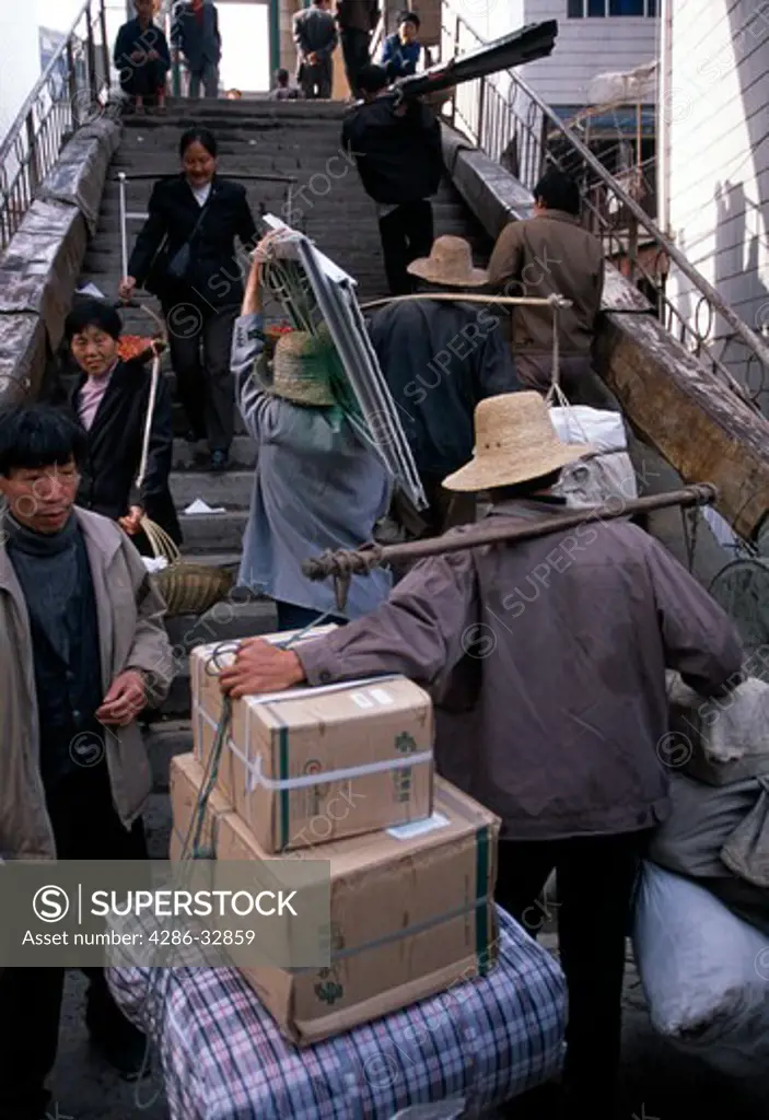 Stick-stick men, porters, carry products up stairs; transport; commerce; morning in town of Wuxi, China, Asia; 042503