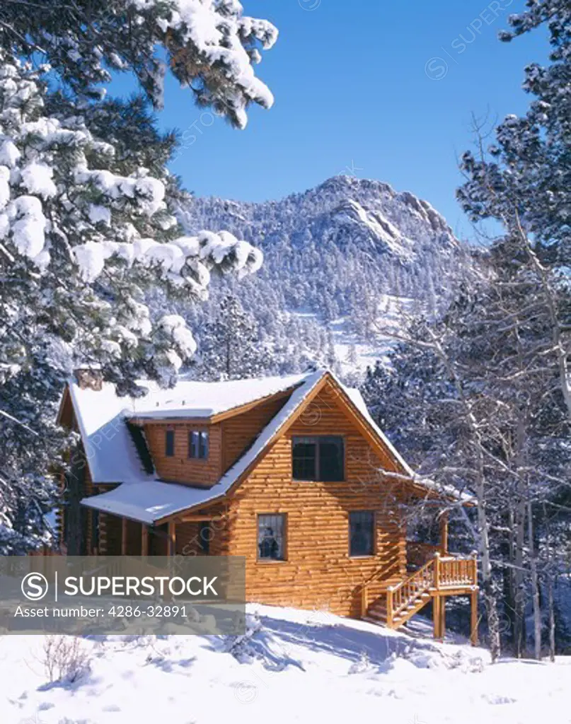 Rustic log cabin home covered in snow, Rocky Mtns, CO