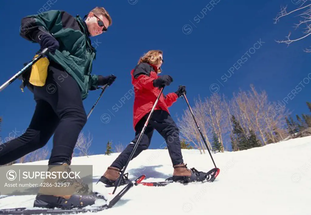A close-up of a couple snowshoeing across the side of a hill in the Rocky Mountains of Colorado