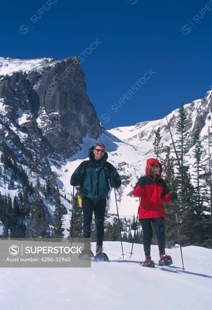 A couple snowshoeing beneath Hallett Peak in Rocky Mountain National Park, Colorado