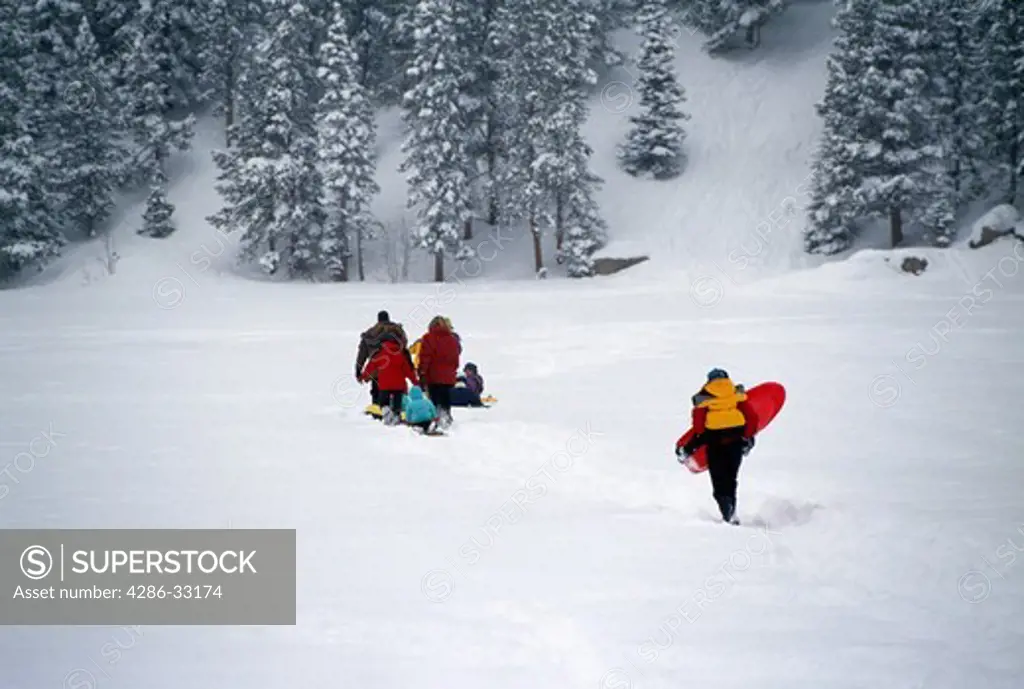 Families crossing snow-covered lake heading toward sledding area, Rocky Mtns, CO