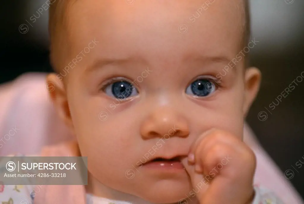 Close-up of an infant looking pensive while sucking thumb, OH