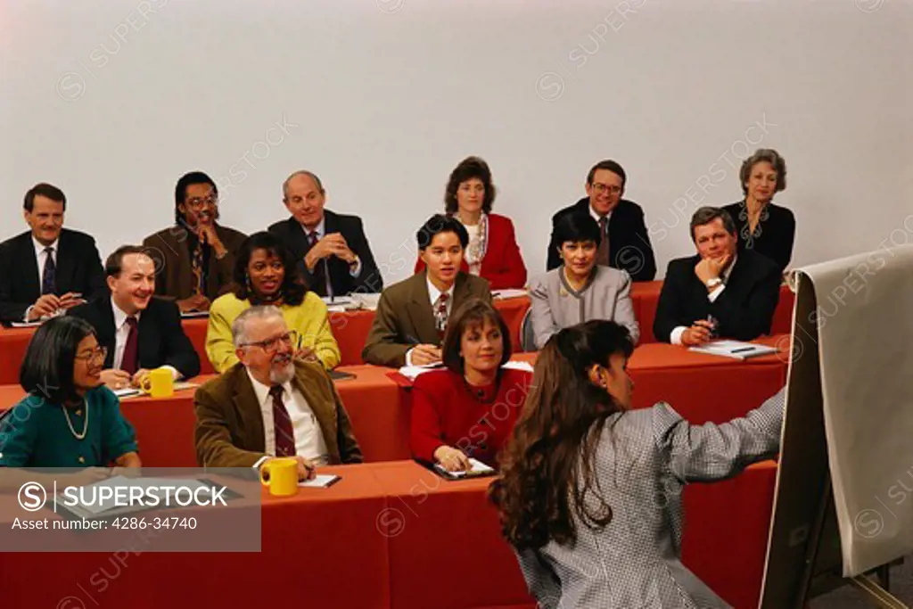 Female executive gives seminar to group of businessmen and women.  We also have a similar shot with a man leading the seminar.